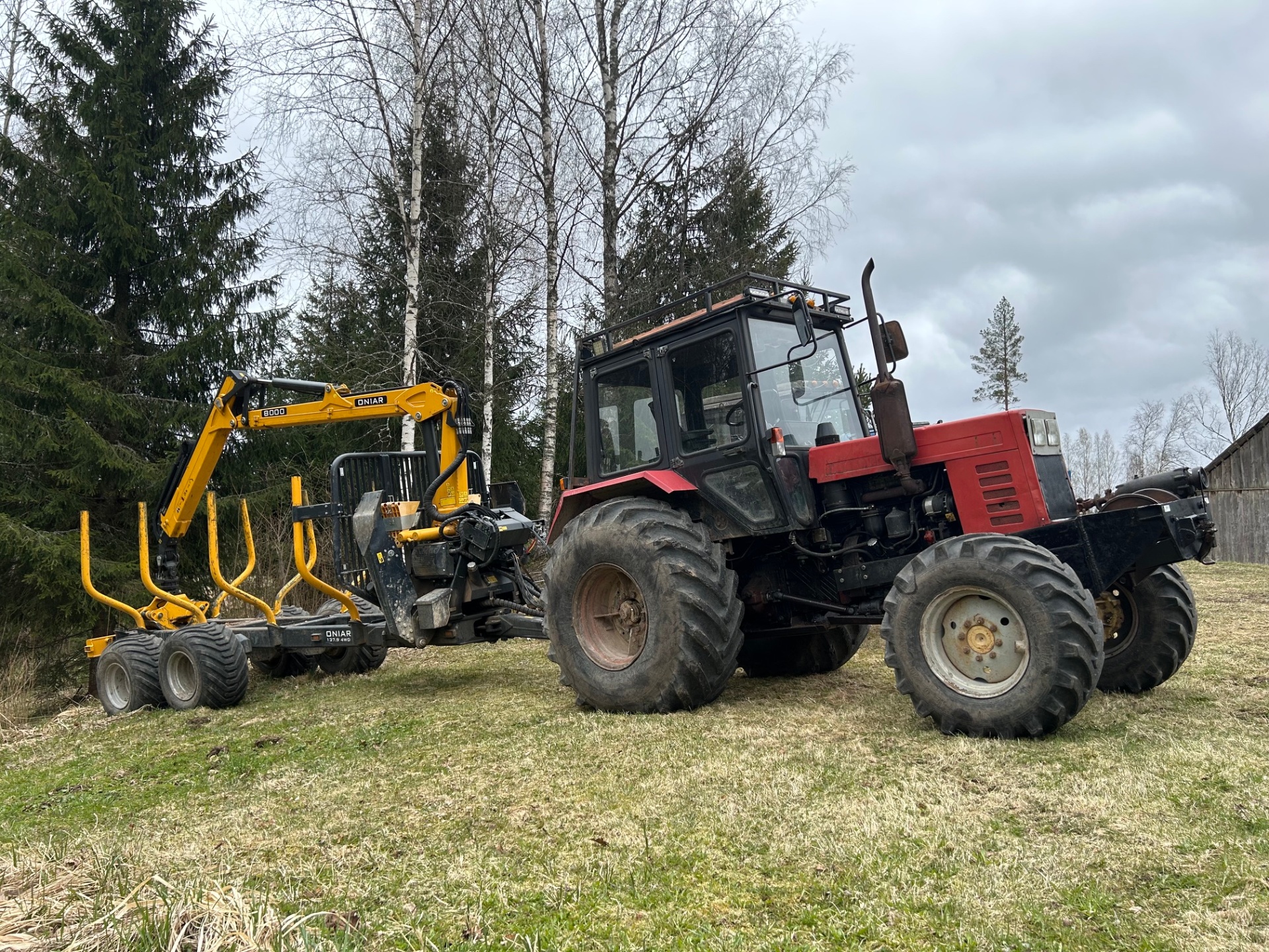 Punane traktor kollase Oniar palgikäruga Võrumaa metsas